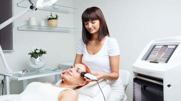 en specialist gennemfører en hudforyngelses session med et apparat